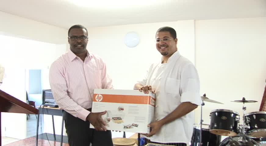 Deputy Premier of Nevis and Ministry of Health Hon. Mark Brantley presents computer system to Master Chef Michael Henville at the Charlestown Primary School’s assembly on March 03, 2014